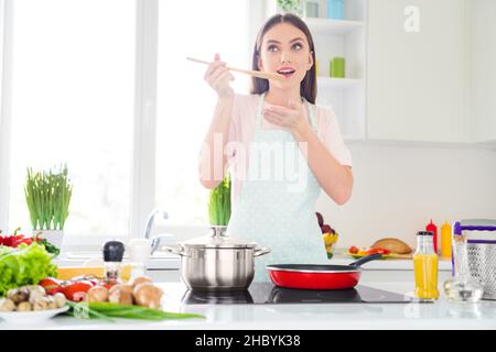 Ritratto di attraente ragazza sognante cheery preparazione perdita di peso cena degustazione delizioso pasto a casa luce bianca cucina al coperto Foto Stock