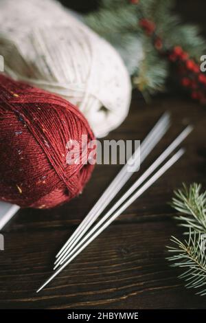 Matasse di filo di lana con aghi su sfondo scuro. Concetto per vita lenta fatta a mano e hygge. Foto Stock