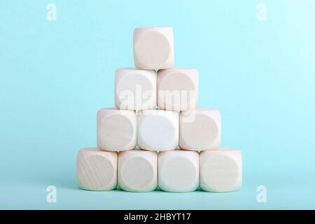 Semplice piramide fatta di piccoli blocchi vuoti di legno, cubetti su sfondo blu chiaro. Triangolo, cubo stack costruito struttura primo piano oggetto, nessuno. B Foto Stock