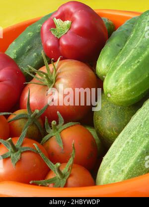 sfondo da cetriolo, pomodoro, pepe. Frutta matura in un piatto sul tavolo Foto Stock