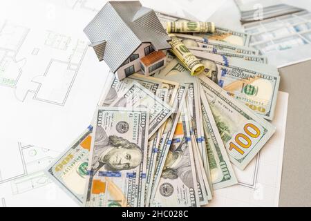 Soldi contro lo sfondo della disposizione della casa. Stipendio per i costruttori. Posti vacanti per i costruttori. Formazione nelle professioni di costruzione. Foto Stock