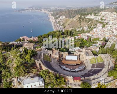 Drone aereo. L'antico teatro greco e la città di Taormina, Sicilia, Italia. Foto Stock