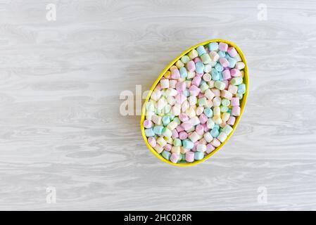 Mini marshmallows multicolore in uovo decorativo di Pasqua, spazio copia per le congratulazioni e desideri Foto Stock