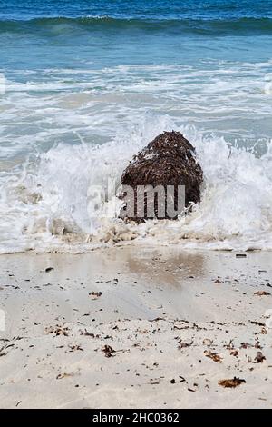Onde contro grandi rocce sulla riva della spiaggia, acque turchesi. Mar Mediterraneo. Isole Baleari, spiaggia sabbiosa, Foto Stock