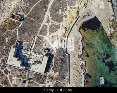 Veduta aerea dell'isola e della spiaggia dell'Isola delle correnti. Faro circondato da acque cristalline di mare a Portopalo di capo Passero, in Sicilia Foto Stock