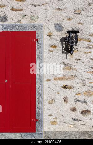 Porta rossa chiusa e luce sul muro di pietra - un display geometrico Foto Stock