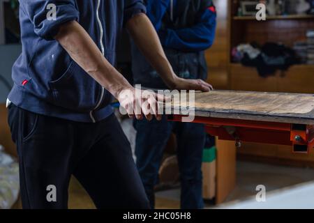 stampa serigrafica. i lavoratori sono pronti ad avviare il processo di stampa. creazione di stampe su maglietta in officina Foto Stock