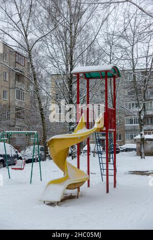 Scivolo per bambini coperto di neve nel cortile di una zona residenziale Foto Stock