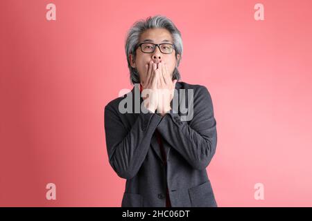 L'uomo asiatico in piedi su sfondo rosa. Foto Stock