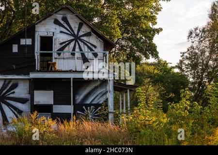 Vecchia casa in legno abbandonata a due piani dipinta con vernice tra la natura Foto Stock