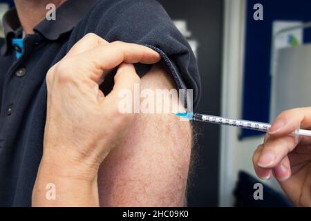 L'infermiere di pratica da un ambulatorio di GP sta somministrando l'iniezione di richiamo del vaccino di BioNTech, Pfizer ad un uomo per proteggere contro l'infezione di COVID-19, durante una clinica di vaccinazione. (127) Foto Stock