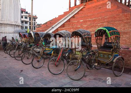 Rickshaws di bicicletta colorati parcheggiati di fronte ad un tempio indù in Piazza Hanuman Dhoka Durbar, Kathmandu, Nepal. Foto Stock