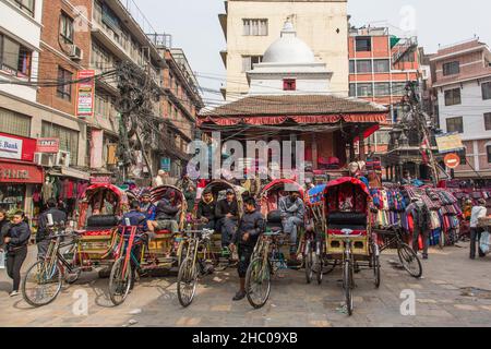 I conducenti di bici in risciò parcheggiati in una piazza a Kathmandu, Nepal, in attesa di passeggeri. Foto Stock