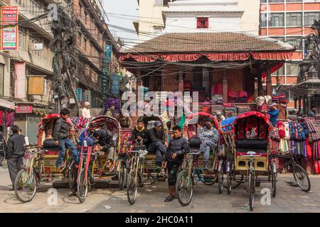 I conducenti di bici in risciò parcheggiati in una piazza a Kathmandu, Nepal, in attesa di passeggeri. Foto Stock