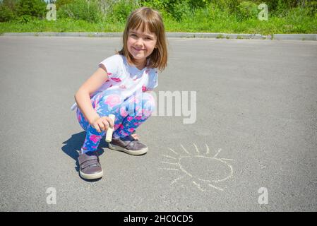 Ritratto all'aperto di un bambino felice con gesso nelle mani, in una giornata estiva soleggiata. Foto Stock