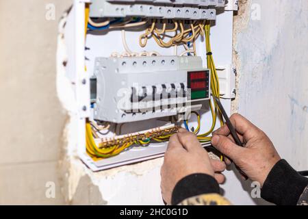 Un elettricista installa un pannello elettrico nella casa. Conduzione di elettricità, accensione e protezione. Foto Stock