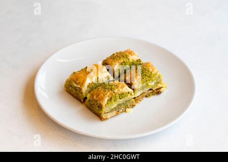 Dessert al pistacchio baklava su sfondo bianco. Dessert dolce turco. Piatto di pistacchio baklava. Sherbet dolce panetteria mediterranea. Chiudi Foto Stock