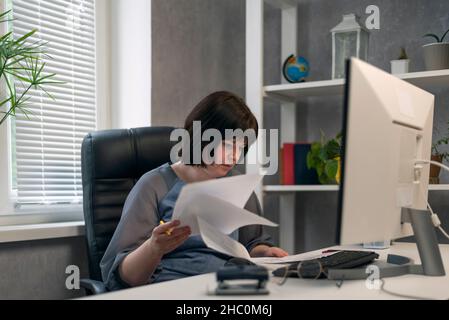 Donna contabile in ufficio lavora con documenti e contratti. Il dipendente prepara un report trimestrale Foto Stock
