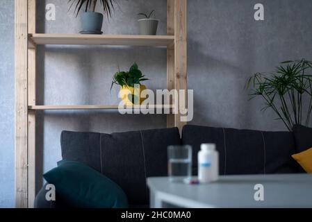 Bottiglia di pillole e bicchiere d'acqua sul tavolo in soggiorno vuoto. Concetto di salute, trattamento Foto Stock