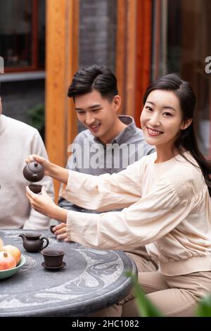 Famiglie felici che bevono il tè e chiacchierano nel cortile Foto Stock