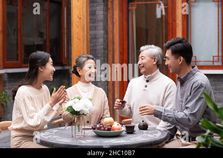 Famiglie felici che bevono il tè e chiacchierano nel cortile Foto Stock