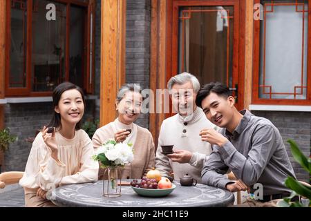 Famiglie felici che bevono il tè e chiacchierano nel cortile Foto Stock