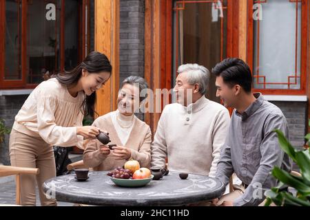 Famiglie felici che bevono il tè e chiacchierano nel cortile Foto Stock