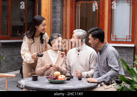Famiglie felici che bevono il tè e chiacchierano nel cortile Foto Stock