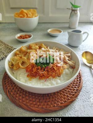 Porridge di pollo con cakwe, pollo grattugiato, cracker, scalogni fritti e condimenti con cipolle primaverili Foto Stock