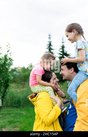 Una coppia sposata con bambini in impermeabile giallo nel cortile posteriore. Vista frontale. Foto Stock