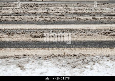 Attraversamento pedonale nevoso, scivoloso e fangoso. Spargimento di sale sulla strada. Foto Stock