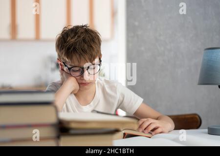 Scolaro fa i suoi compiti. Ragazzo legge il libro di testo. Apprendimento a distanza. Homeschooling. Harry Potter moderno Foto Stock