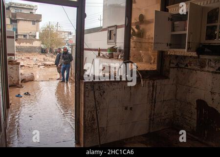 Erbil, Iraq. 17th Dic 2021. La gente si trova al di fuori di una casa colpita dalle inondazioni che hanno colpito Erbil, nel nord dell'Iraq, il 17 dicembre 2021. Il bilancio delle vittime di inondazioni improvvise causate da piogge torrenziali nel nord dell'Iraq è salito a 11 il venerdì. Credit: Dalshad al-Daloo/Xinhua/Alamy Live News Foto Stock