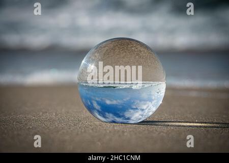 Globo di vetro sulla spiaggia del Mar Baltico in Zingst in cui è raffigurato il paesaggio. Il tramonto crea un'atmosfera calda e luminosa Foto Stock