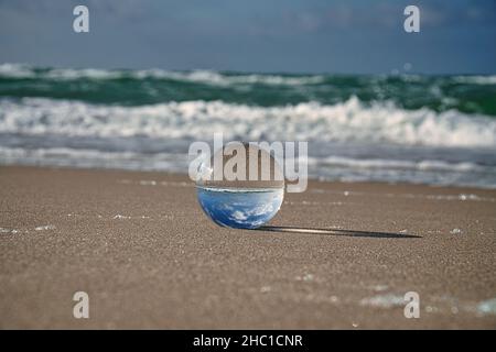 Globo di vetro sulla spiaggia del Mar Baltico in Zingst in cui è raffigurato il paesaggio. Il tramonto crea un'atmosfera calda e luminosa Foto Stock