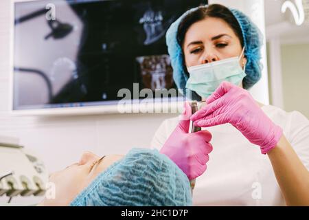 Primo piano di una foto di un dentista medico nella preparazione uniforme di apparecchiature dentarie per iniziare a lavorare con un paziente nella sua clinica d'ufficio. Foto Stock