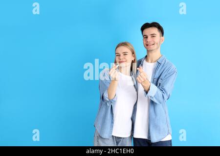 Coppia carina con cuori delle dita su sfondo blu Foto Stock