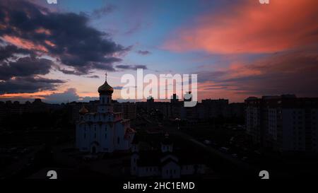 Cambia da giorno a notte traffico di transizione su strada e case residenziali a più piani. Paesaggio urbano Minsk Skyline con la Chiesa Ortodossa Russa. 4K nuvoloso Foto Stock