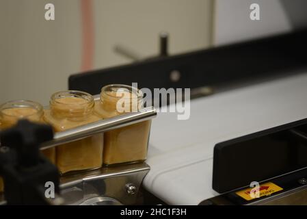 Vasetti di miele cremato in una linea di confezionamento presso una fabbrica commerciale di miele Foto Stock