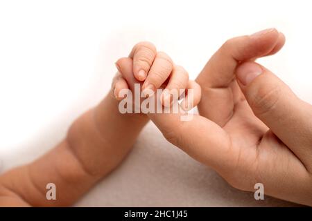 Il neonato bianco si chiude con una presa salda sul dito del genitore Foto Stock