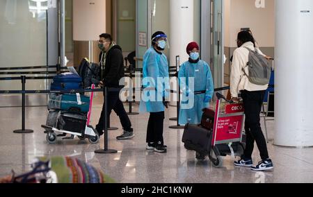 (211221) -- MISSISSAUGA (CANADA), 21 dicembre 2021 (Xinhua) -- i viaggiatori internazionali che indossano le maschere facciali sono visti alla sala degli arrivi dell'aeroporto internazionale Pearson di Toronto a Mississauga, Ontario, Canada, il 21 dicembre 2021. Il Canada ha segnalato 9.597 nuovi casi COVID-19 martedì pomeriggio, portando il totale cumulativo a 1.907.180 casi con 30.082 morti, secondo CTV. (Foto di Zou Zheng/Xinhua) Foto Stock