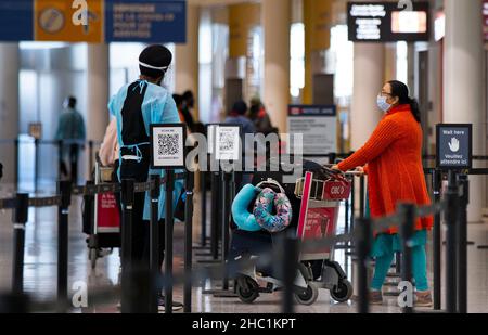 (211221) -- MISSISSAUGA (CANADA), 21 dicembre 2021 (Xinhua) -- un viaggiatore internazionale che indossa una maschera facciale cammina con il bagaglio a un COVID-19 sito di prova presso l'aeroporto internazionale Pearson di Toronto a Mississauga, Ontario, Canada, il 21 dicembre 2021. Il Canada ha segnalato 9.597 nuovi casi COVID-19 martedì pomeriggio, portando il totale cumulativo a 1.907.180 casi con 30.082 morti, secondo CTV. (Foto di Zou Zheng/Xinhua) Foto Stock