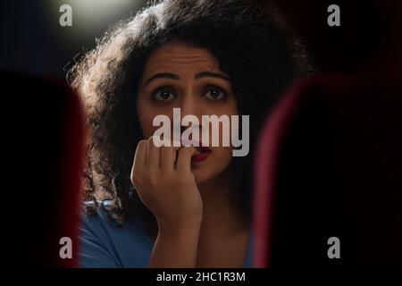 Ritratto di una donna scioccata e sorpresa mentre si guarda il film horror nel cinema Foto Stock
