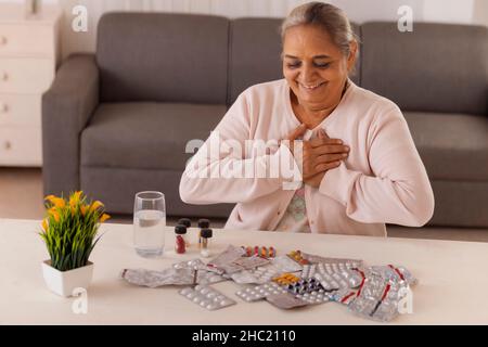 Donna anziana che sta per prendere la medicina tenuta sul tavolo centrale Foto Stock