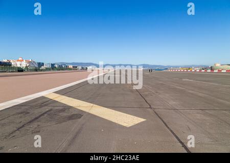 Gibilterra, Regno Unito - 20 agosto 2021. Locali e auto che attraversano la pista all'aeroporto di Gibilterra con la Rocca di Gibilterra sullo sfondo. Gibilterra, Foto Stock