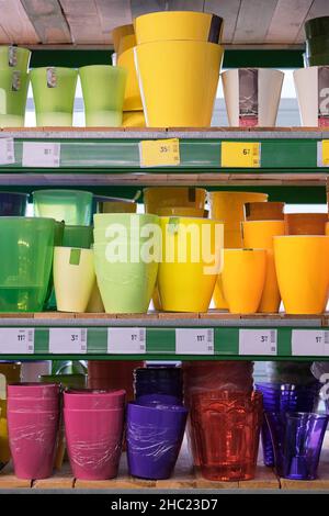 Pentole per le casalinghe sono vendute al deposito. File di pentole colorate diverse per piante interne su scaffali in un supermercato. Foto Stock