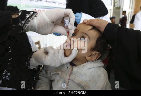 (211219) -- SANAA, 19 dicembre 2021 (Xinhua) -- un operatore sanitario dà un vaccino antipolio ad un bambino durante una campagna di vaccinazione di emergenza a Sanaa, Yemen, 18 dicembre 2021. In collaborazione con l'Organizzazione Mondiale della Sanità, le autorità sanitarie delle province settentrionali dello Yemen hanno lanciato sabato una campagna di vaccinazione contro il morbillo, la polio e la rosolia per bambini. (Foto di Mohammed Mohammed/Xinhua) Foto Stock