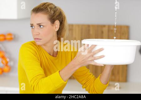 donna che guarda i danni dopo una perdita del tubo dell'acqua Foto Stock