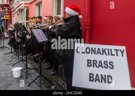 Clonakilty, West Cork, Irlanda. 23rd Dic 2021. La Clonakilty Brass Band ha giocato i caroli di Natale su Clonakilty Main Street oggi, il giorno prima della vigilia di Natale, che ha tirato una grande folla di spettatori. Credit: AG News/Alamy Live News Foto Stock