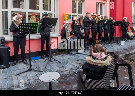 Clonakilty, West Cork, Irlanda. 23rd Dic 2021. La Clonakilty Brass Band ha giocato i caroli di Natale su Clonakilty Main Street oggi, il giorno prima della vigilia di Natale, che ha tirato una grande folla di spettatori. Credit: AG News/Alamy Live News Foto Stock